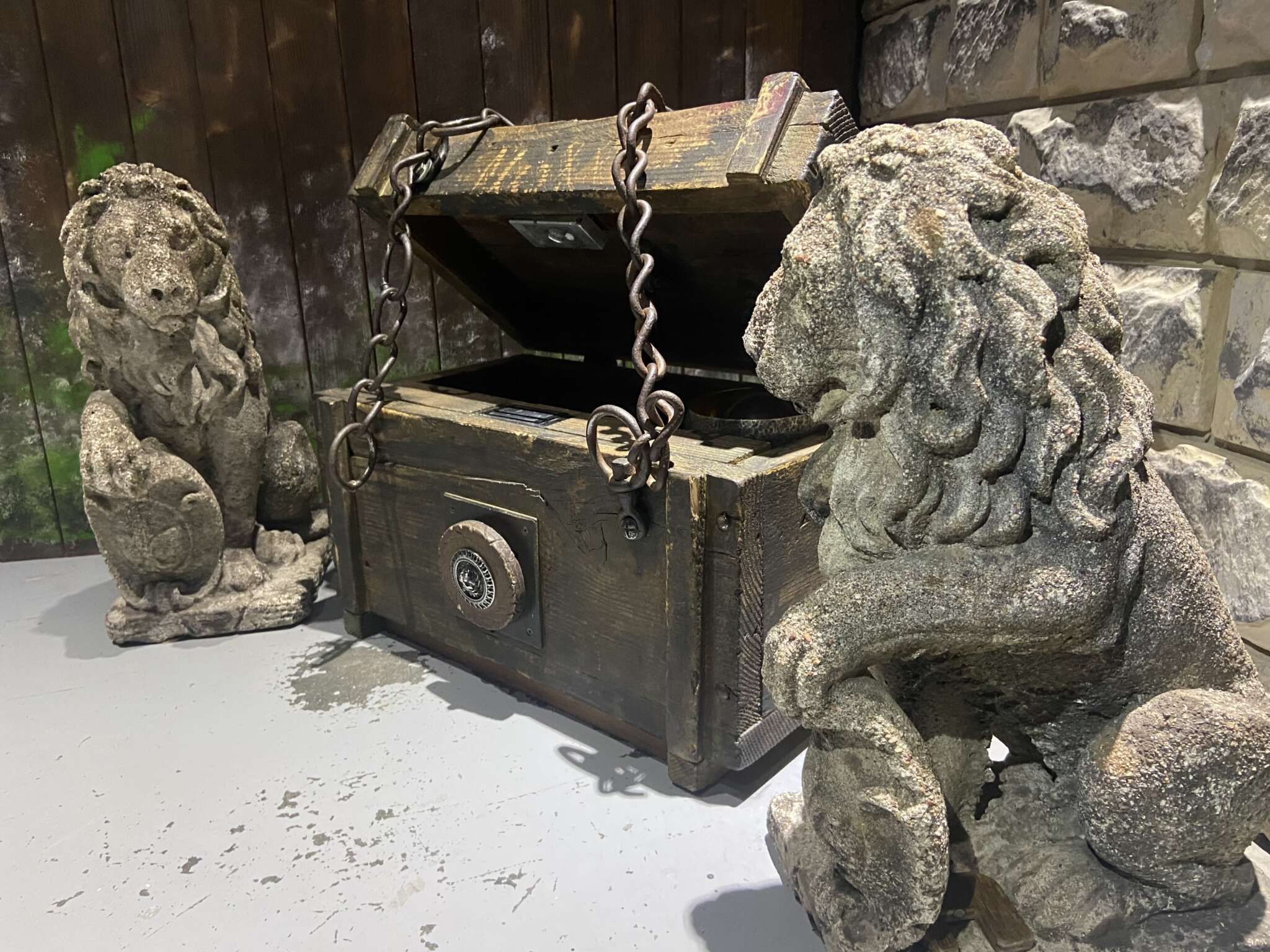 Coffre médiéval entouré de statues de lions dans l’escape game Le Château Noir près d’Annecy